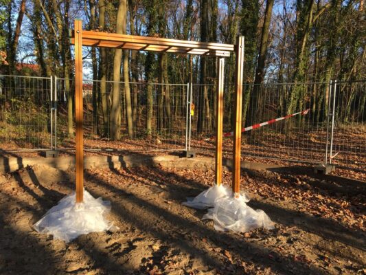 Neu installiertes Holz-Klettergerüst im herbstlichen Park, umgeben von Bauzäunen und Warnband.