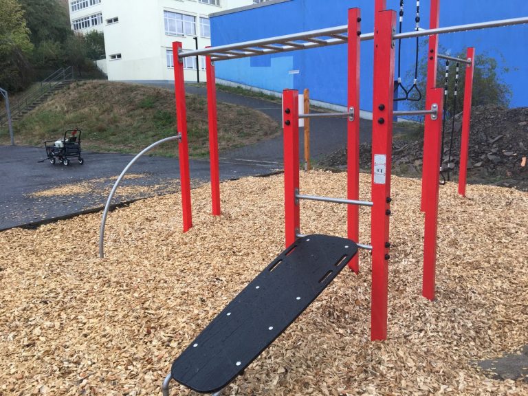 Outdoor-Spielplatz mit rot-schwarzer Kletterstruktur, ideal für Kinderaktivitäten und sportliche Betätigung.