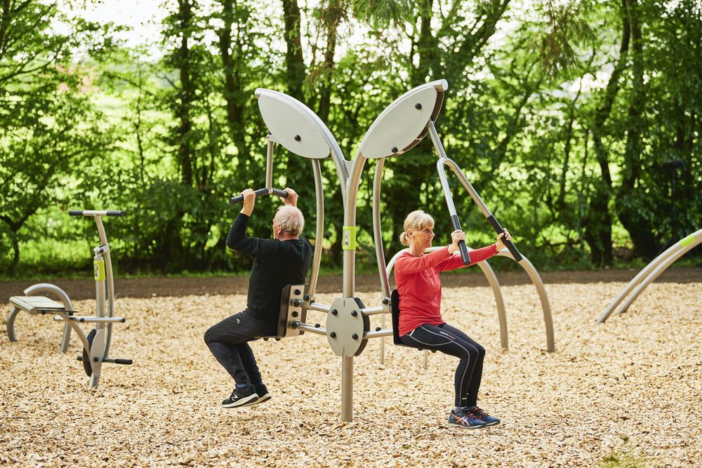 Outdoor-Fitnessgeräte im Wald: Senioren beim Krafttraining, Natur, Gesundheit, Wohlbefinden, Aktivität.