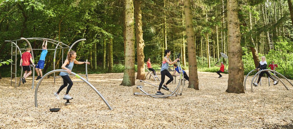 Outdoor-Fitnessstudio im Wald: Natur, Bewegung, moderne Geräte, Menschen beim Training im Grünen.