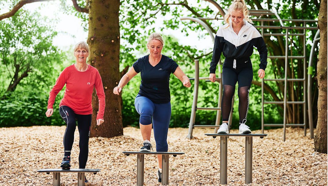 Drei Frauen beim Outdoor-Training im Park auf Plattformen, Fitness, Natur, Sportbekleidung.